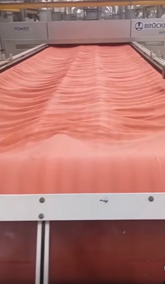 Coral dyed fabric running through the stenter