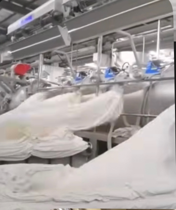 Freshly dyed white fabric moving along the finishing line